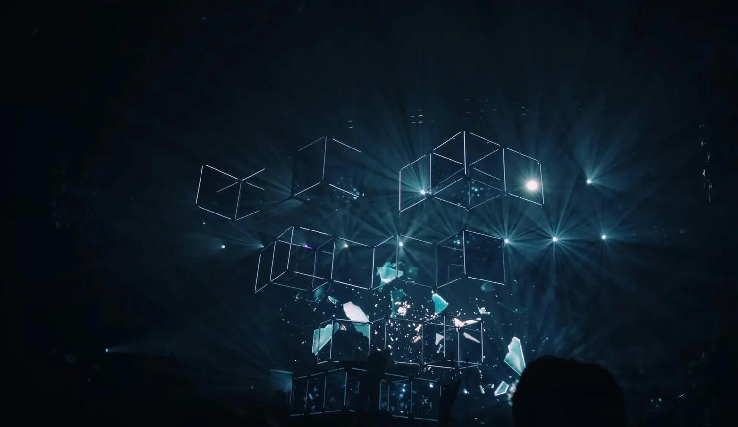Digital light cubes suspended in a dark space with glowing beams and abstract visuals.